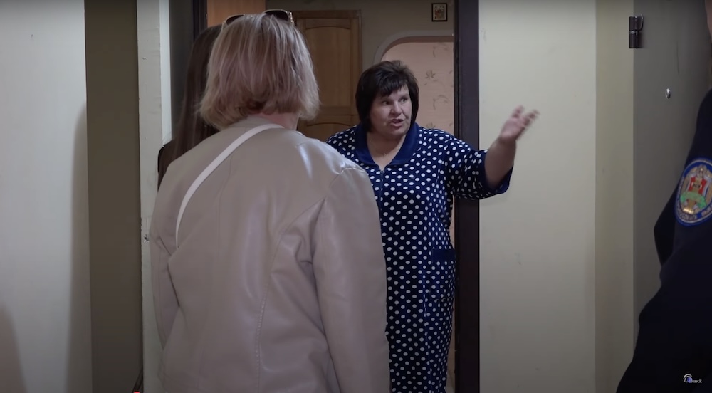 Соседка (в халате) рассказывает владелице квартиры Оксане и судебным приставам о проблемах, связанных с захламленной мусором квартирой. Скриншот с сюжета ТРК «Пинск».