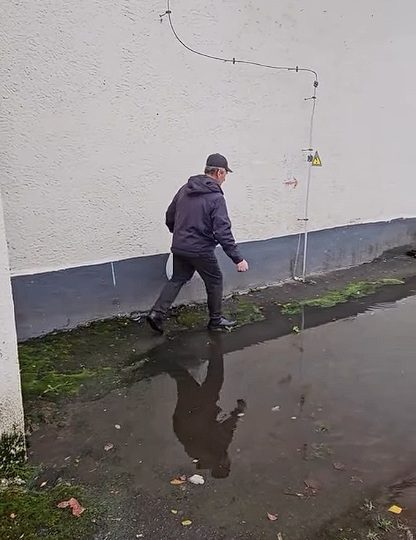 Дзядуля спрабуе абысці лужу каля жылога дома