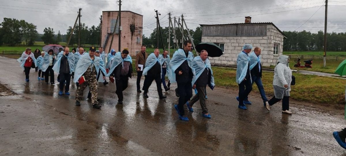 люди в дождевиках ходят возле ферм